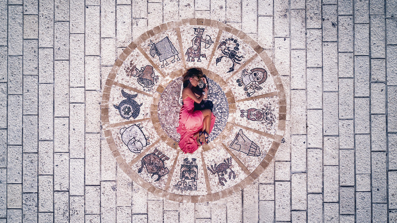 A woman laying in the middle of a zodiac circle