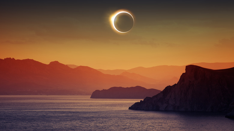 Solar eclipse over mountains and water 