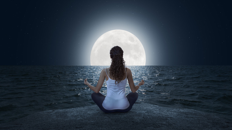 Woman meditating in front of moon