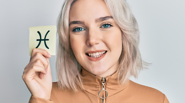 woman holding Pisces symbol card