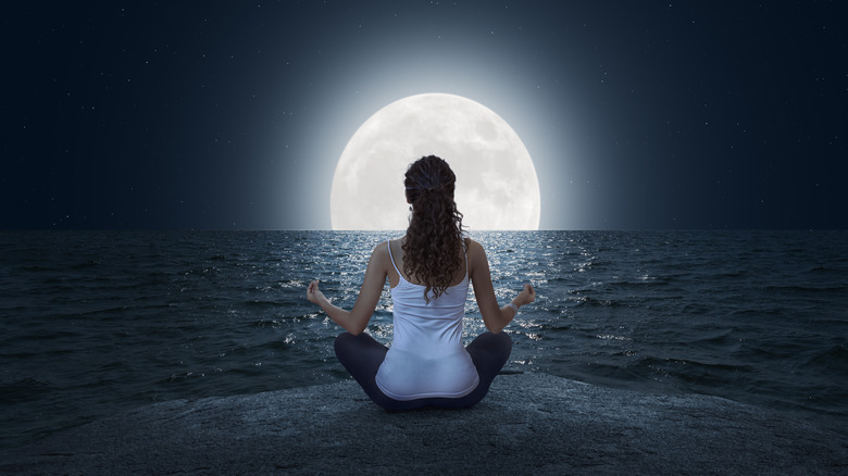 Woman meditating near full moon