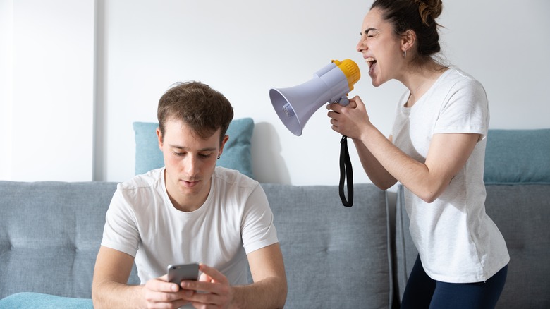A man texting while a woman yells at him