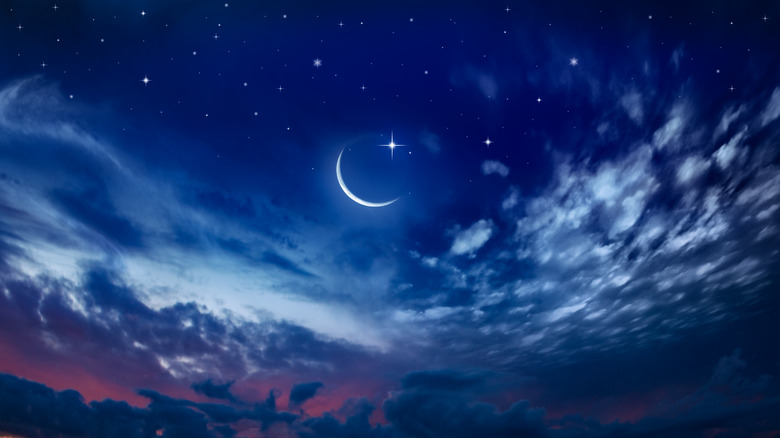 New moon crescent in cloudy sky with star 