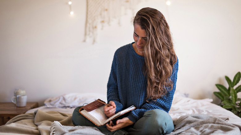 woman sitting on her bed writing