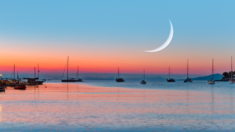 A new moon over the water at sunset. 