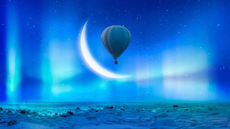 A crescent moon in the sky with a hot air balloon. 