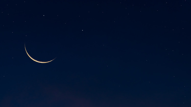 New moon crescent in clear sky with stars