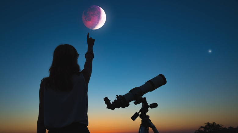 A person pointing at a lunar eclipse 