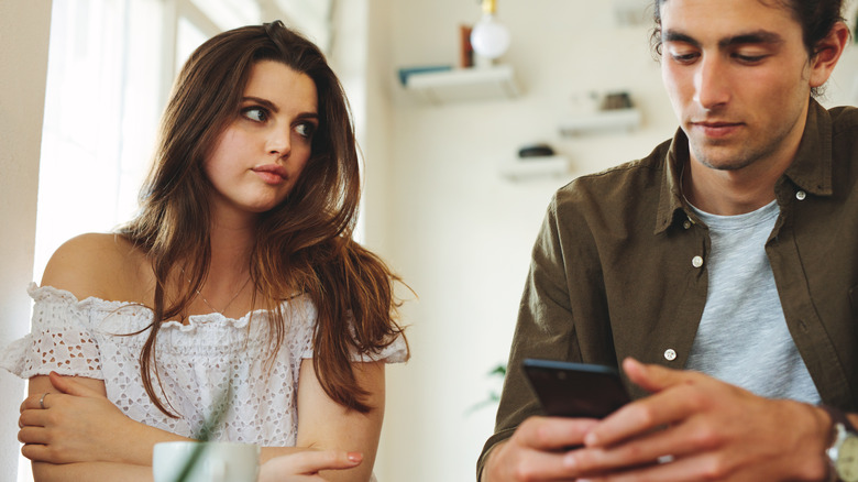 woman looks at man on phone