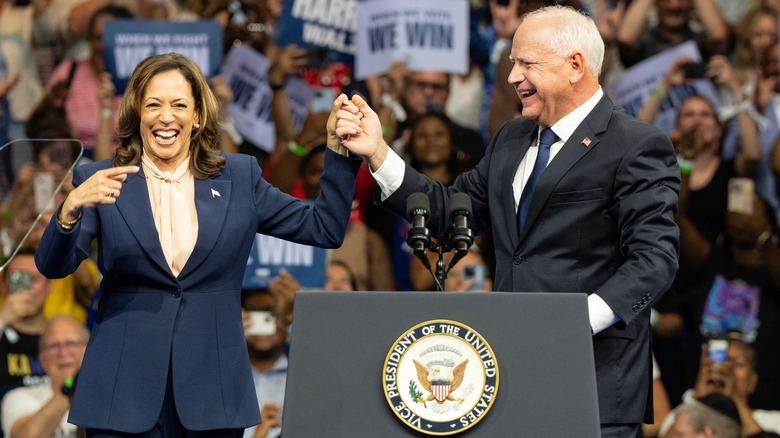 Kamala Harris holding Tim Walz's hand up at a rally