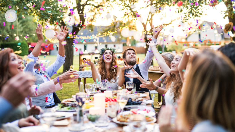 guest throw confetti around table at outdoor wedding reception