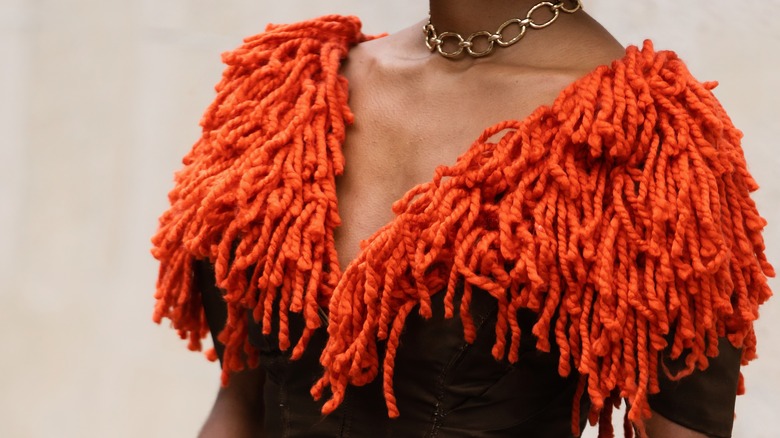 Model wearing orange fringe top