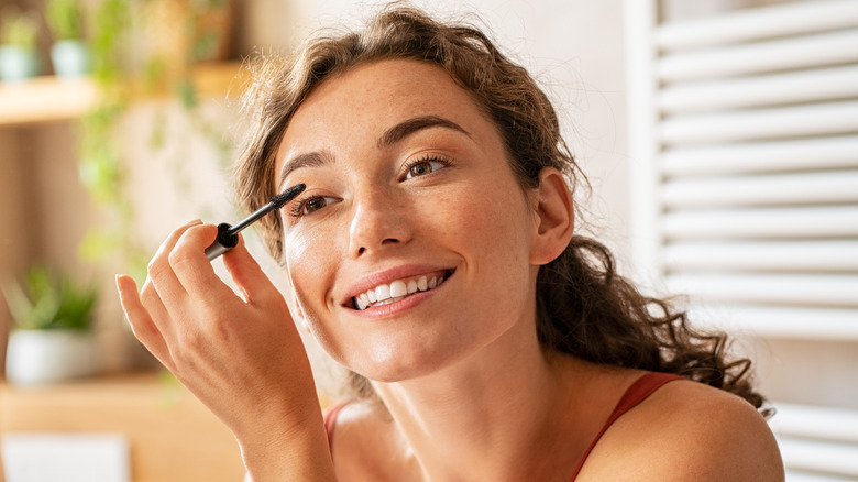 A woman applying mascara 