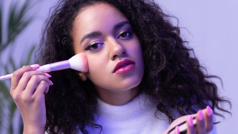 biracial woman with oblong face applying makeup