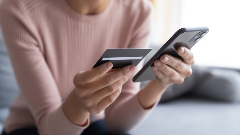 person holding credit card and smartphone while doing online shopping