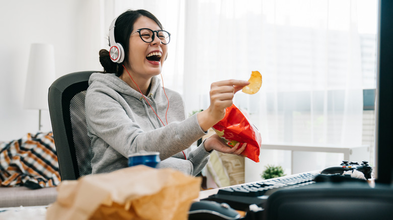 A woman eating snacks at her desk. 