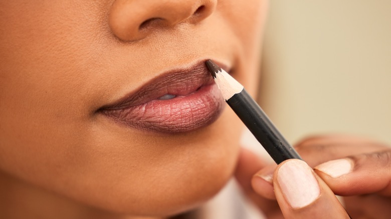 Woman outlining with brown lipliner
