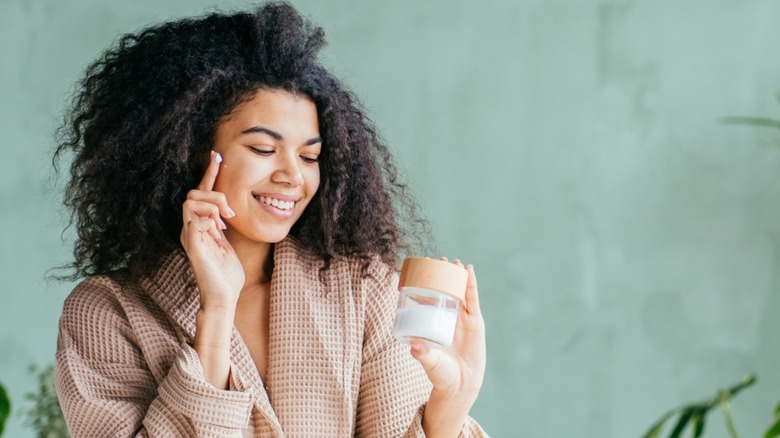 Woman applying lotion on her face