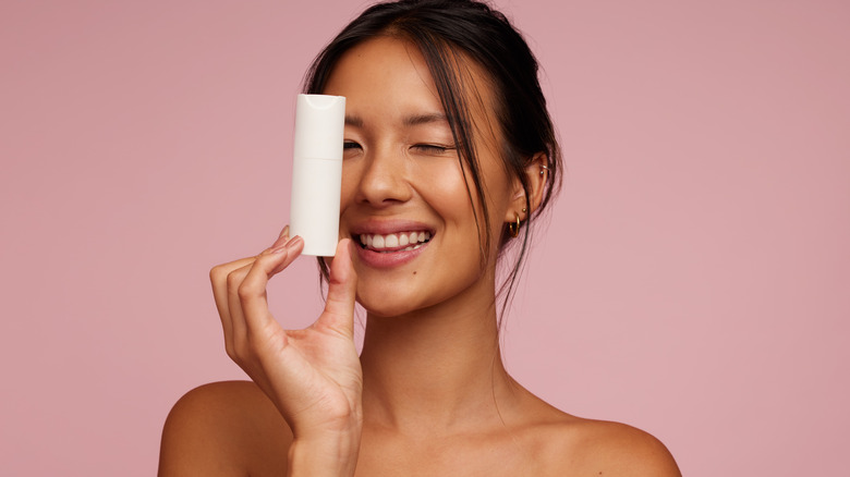 Woman holding a skincare item in front of her face