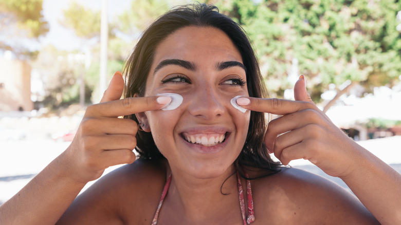 Woman smiling applying sunscreen