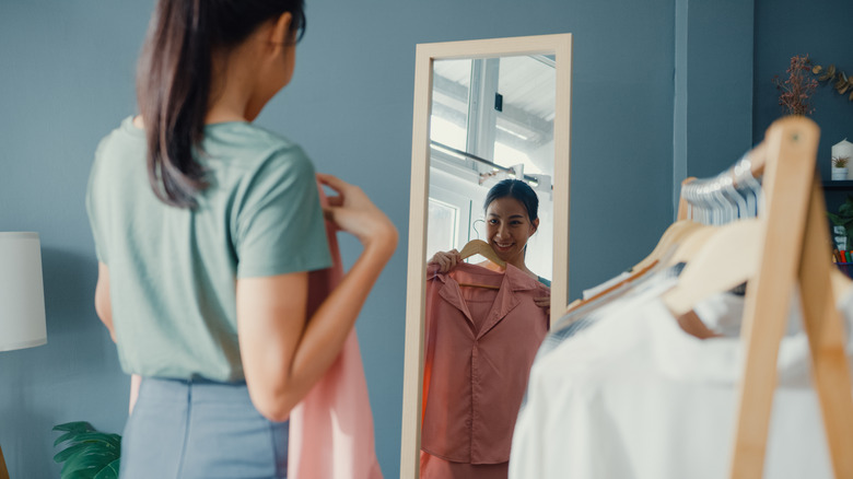 Woman trying on clothing in front of a mirror