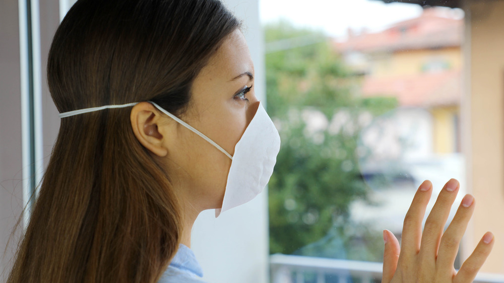 Woman wearing face mask looking out window