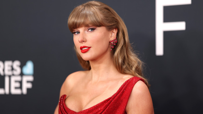 A close up of Taylor Swift posing at the 2025 Grammy Awards in a red dress