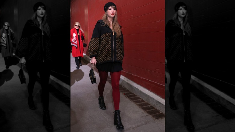 Taylor Swift entering the Arrowhead Stadium in a black outfit with maroon tights
