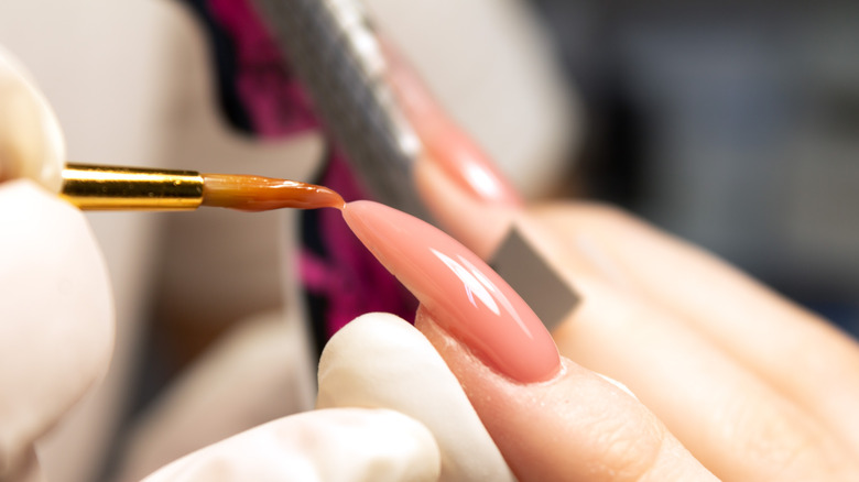 Acrylic nail being shaped with a brush