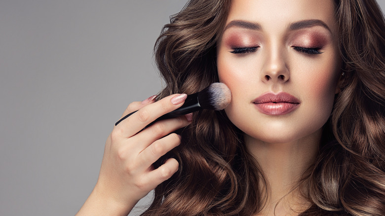 Woman applying powder to face 