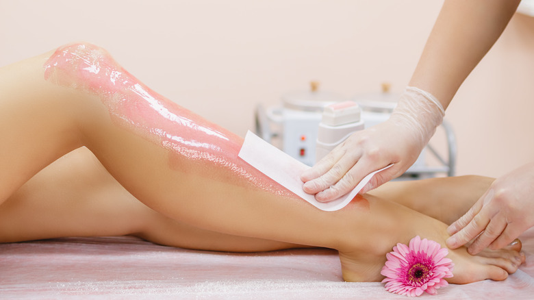 Person getting their hair waxed off with pink wax 