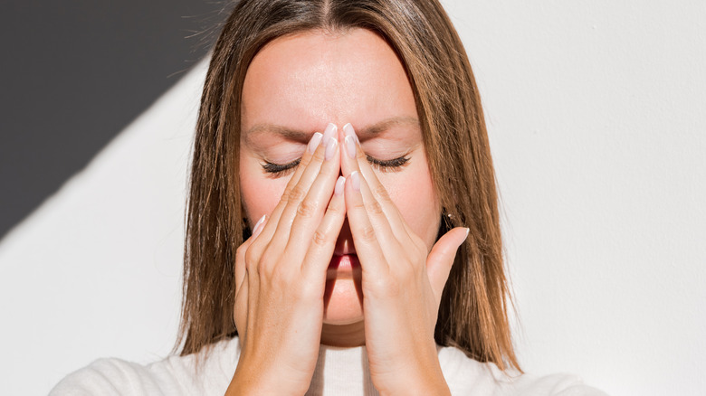 woman holds nose sinuses