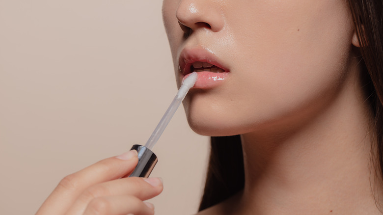 Woman using wand to put on lip gloss
