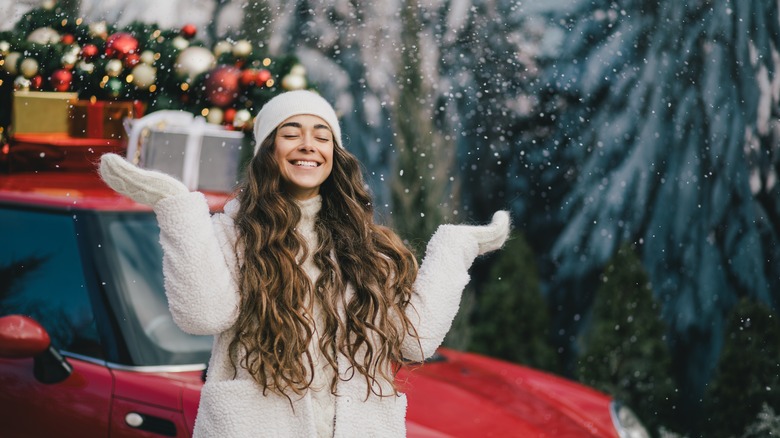 woman standing in front of a red truck with snow and holiday decorations