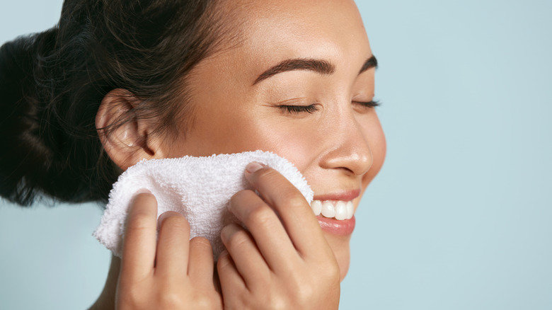 Woman running a washcloth over her face
