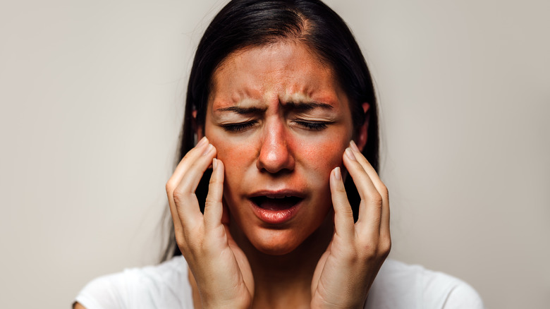 A woman clutching at her face in pain