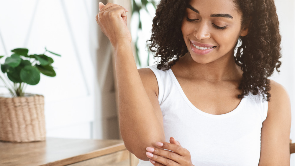 Woman moisturizing her elbow