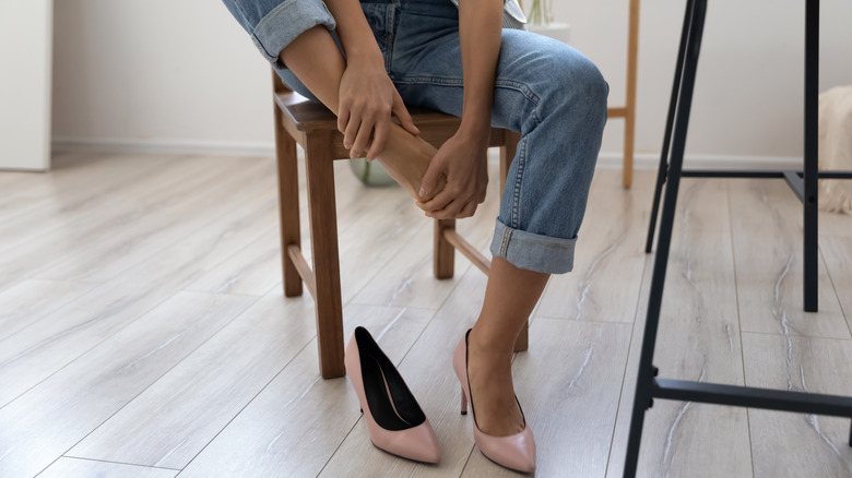 woman taking off her shoes to rub her feet 