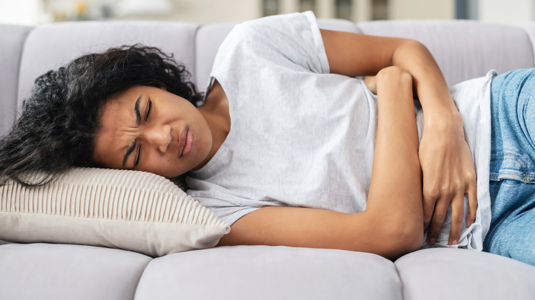 Woman holding stomach and grimacing in pain