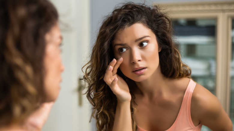 Woman checking the fine lines around her eyes in the mirror