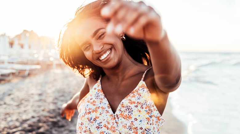 Smiling woman swinging arms by the water 