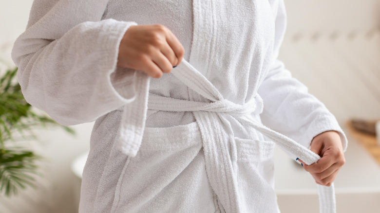 Close-up of woman tying belt of bathrobe