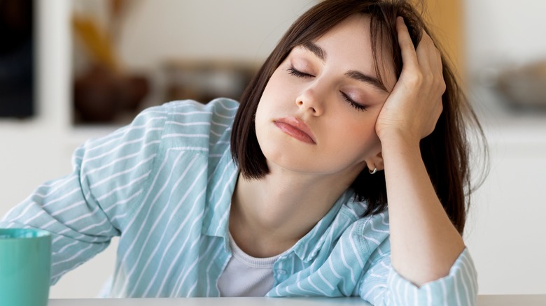 tired woman holding mug eyes closed