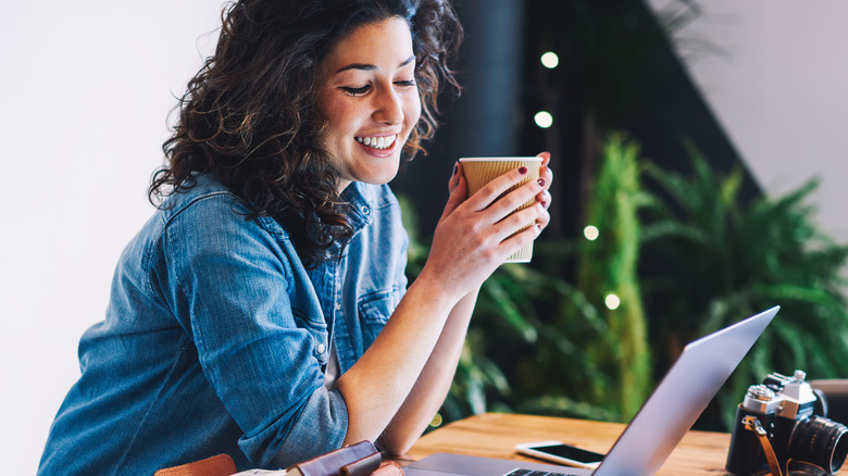 Woman drinking hot coffee while working