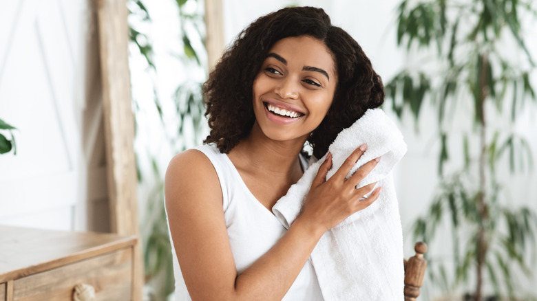 Woman blotting her hair with a white towel.