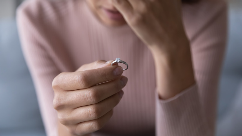 sad woman holding wedding ring