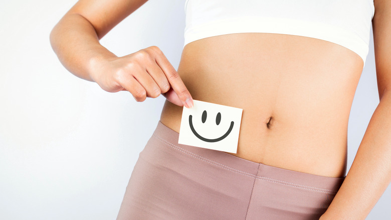 Woman with a smiley face next to her stomach