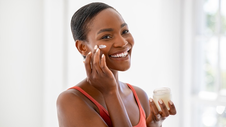 woman applying cream to face