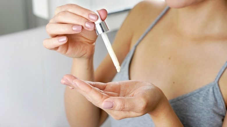 Woman holding dropper of skin serum