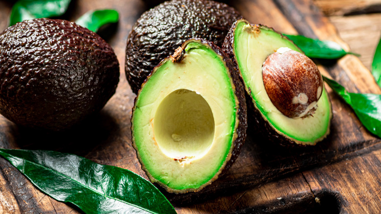 avocado cut in half on cutting board 